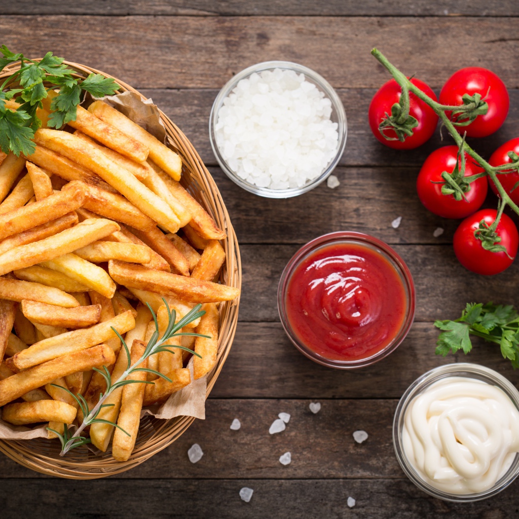 Картофель фри на столе соусом, солью и помидорами 