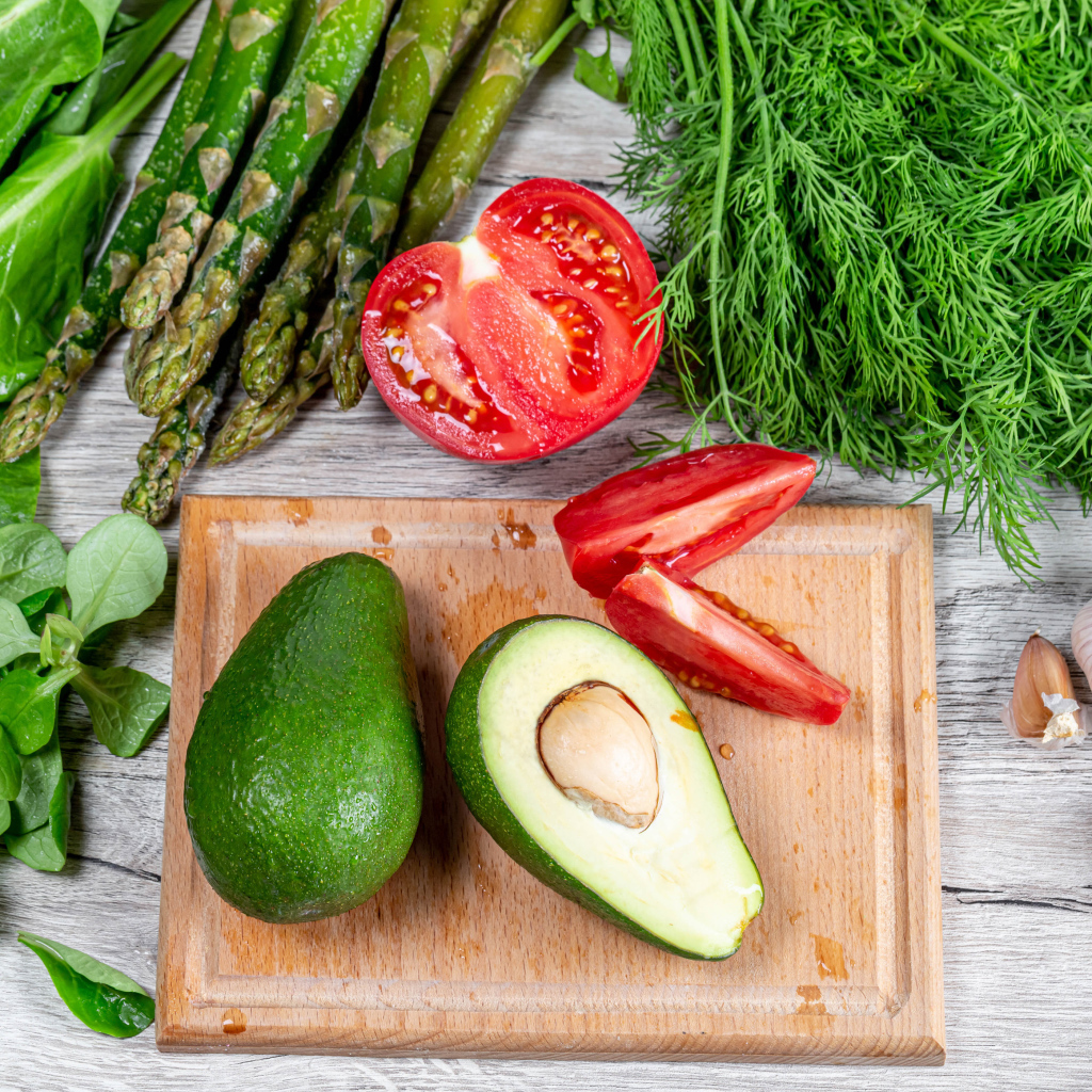 Свежая зелень на столе с авокадо, помидором и чесноком