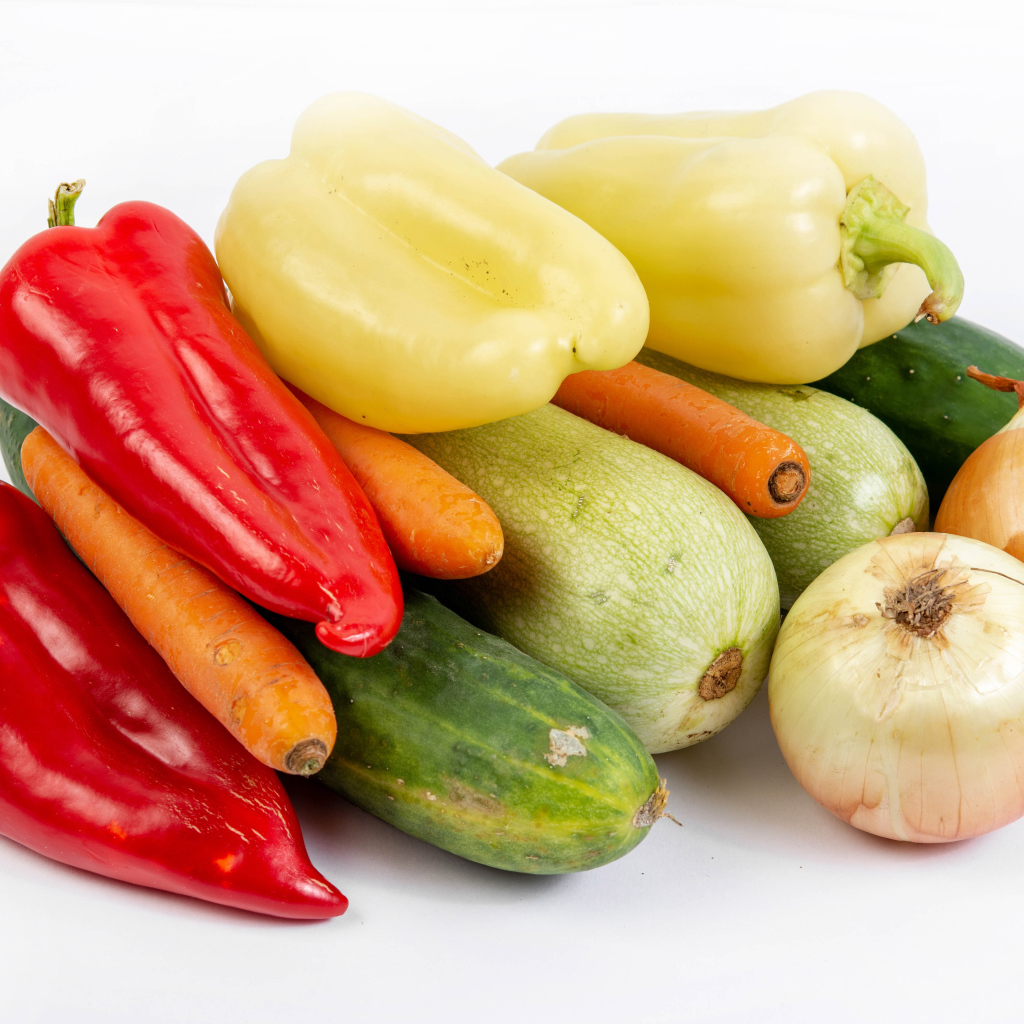 Свежие кабачки, огурцы, морковь, перец и лук на белом фоне