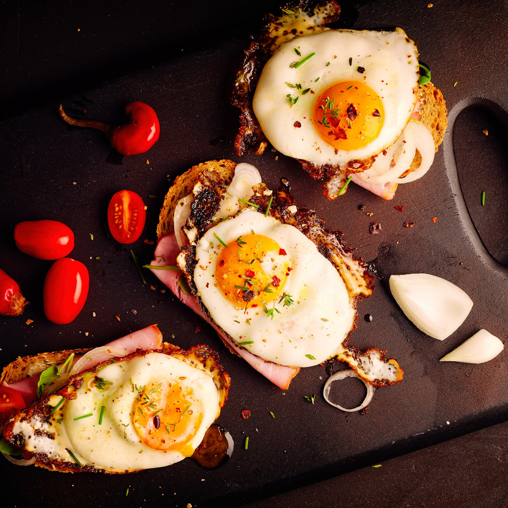 Fried eggs on sandwiches on a cutting board