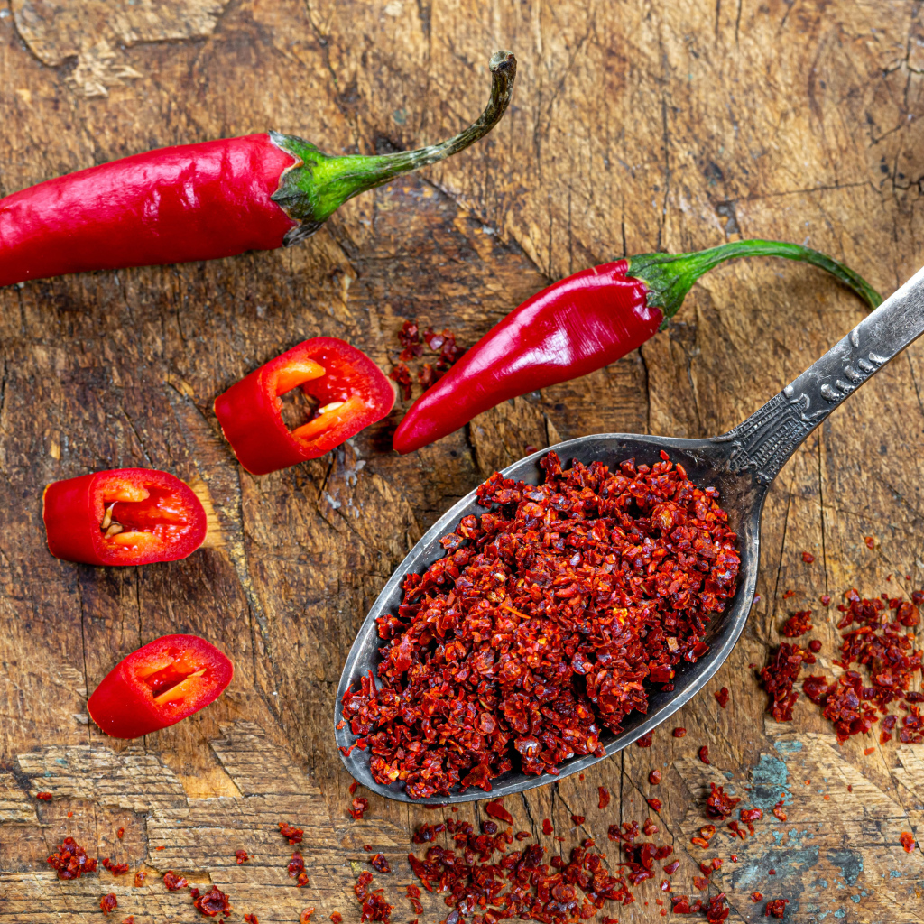 Молотый красный перец на ложке на столе 