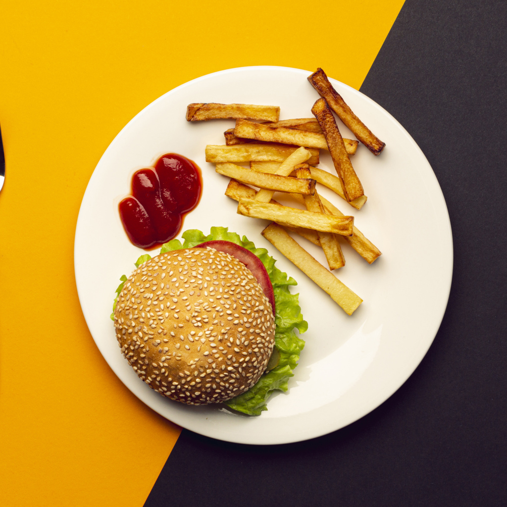 Гамбургер на белой тарелке с соусом и картофелем фри