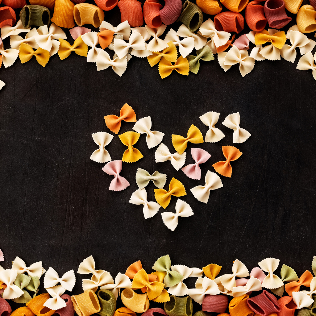 Сердце из разноцветных макарон на черном столе 