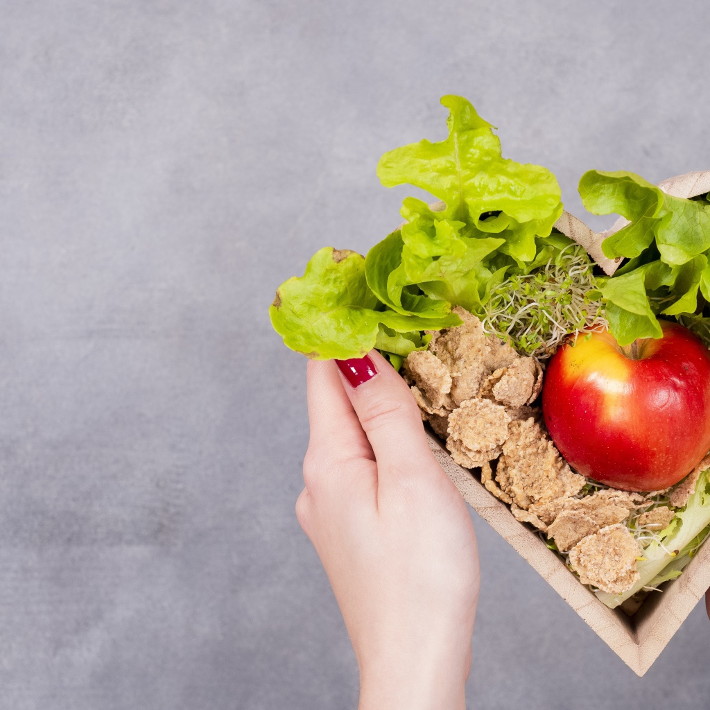 Коробка в форме сердца с яблоком и листьями салата 