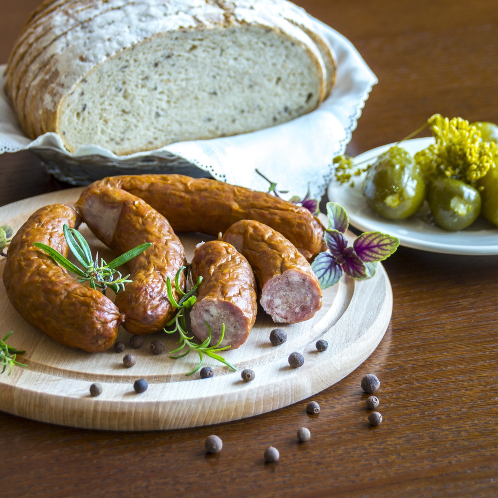 Домашняя колбаса на столе с хлебом и маринованными огурцами