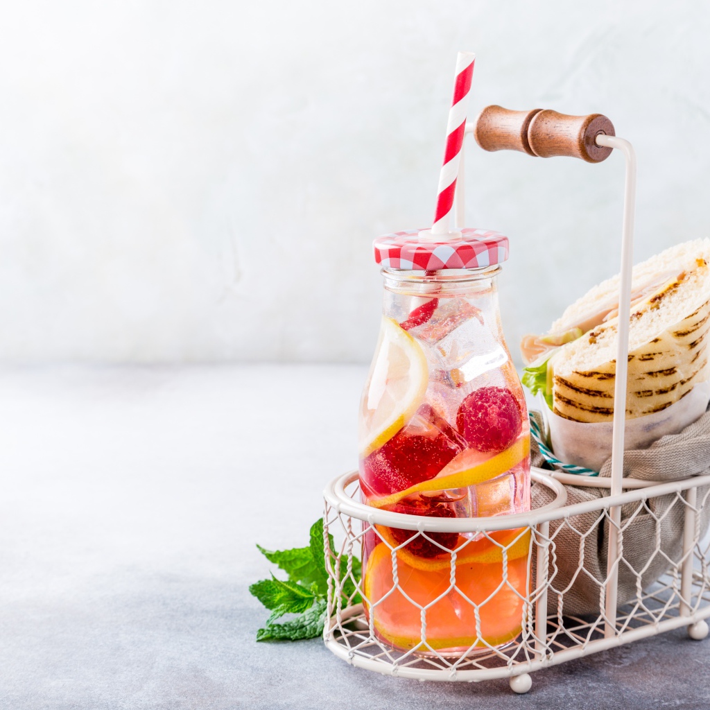 Банка с лимонадом в маленькой корзине с сэндвичем 