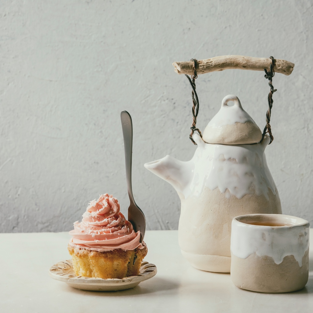 Чайник с чашкой на столе с кексом