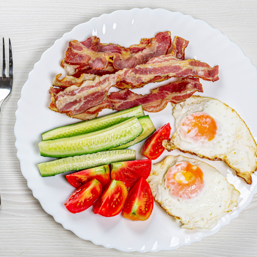 Большая белая тарелка с беконом, огурцами, помидорами и яичницей 