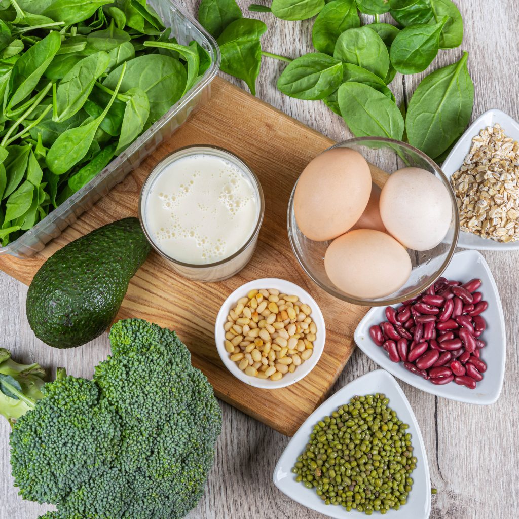 Бобовые, авокадо, базилик, яйца молоко и брокколи на столе