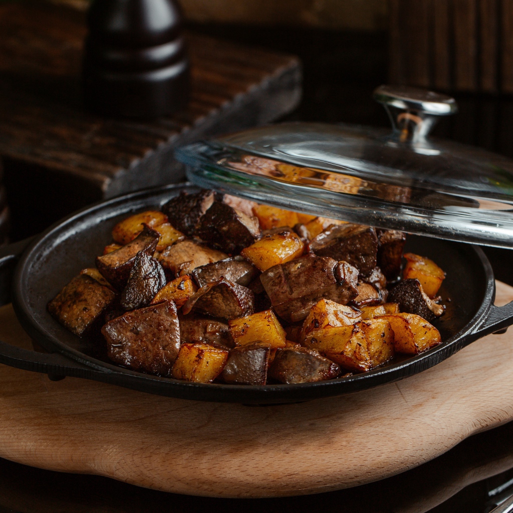 Печень с картофелем в сковороде на столе