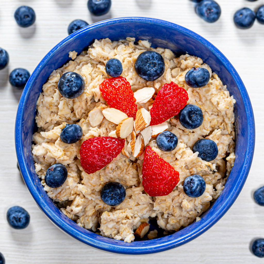 Овсяная каша в тарелке с ягодами черники и клубники 