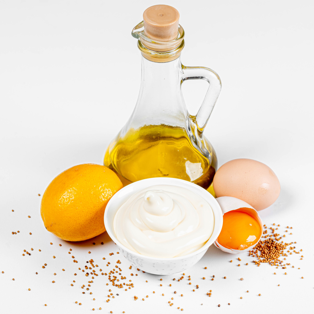 Оливковое масло, яйца и лимон на белом фоне с майонезом