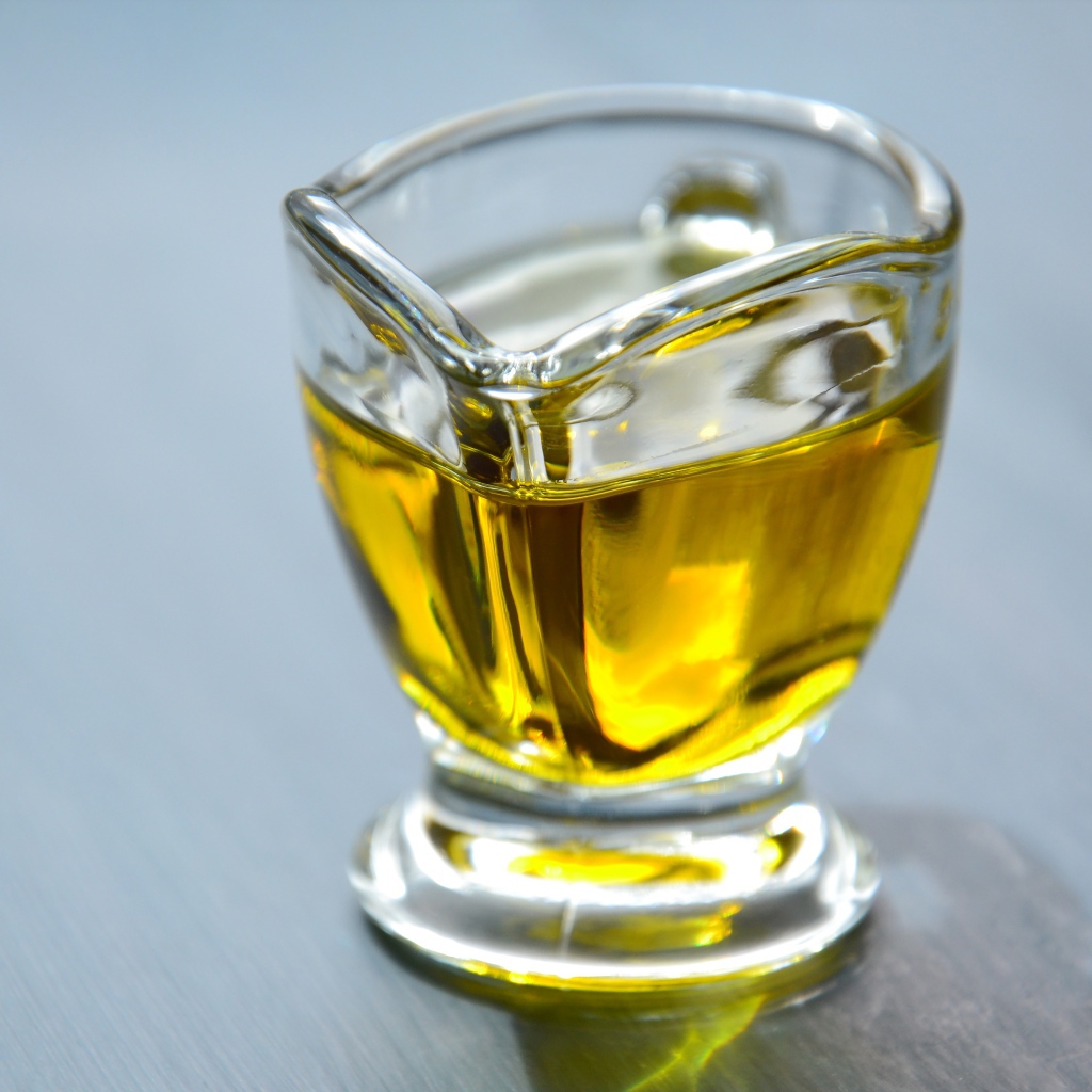 Оливковое масло в стеклянной вазе на столе 