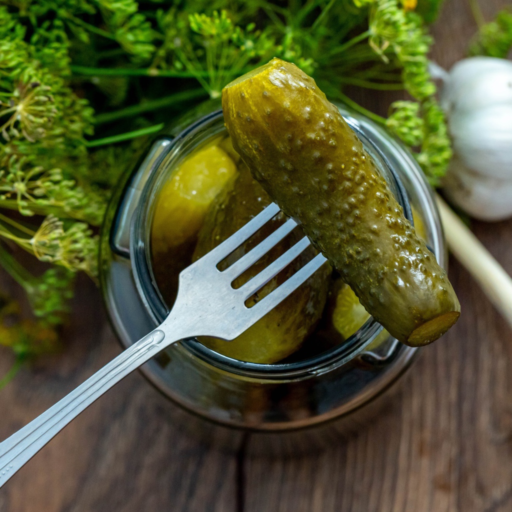 Pickled cucumbers in a jar on a table with garlic and dill