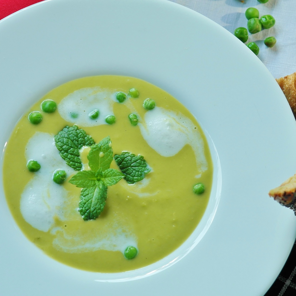 Суп пюре с зеленым горошком в белой тарелке 