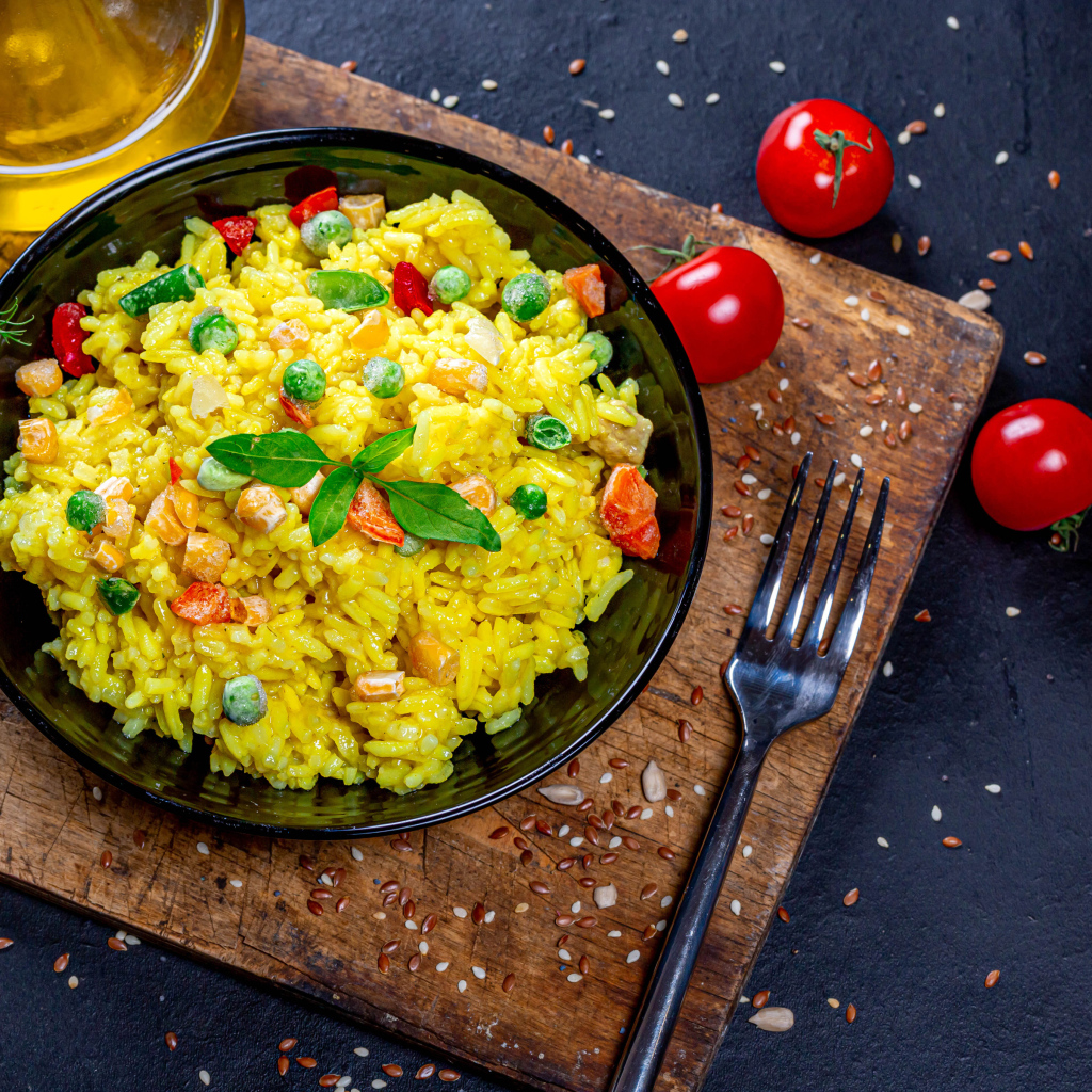 Рис с овощами на столе с маслом, зеленью и помидорами 