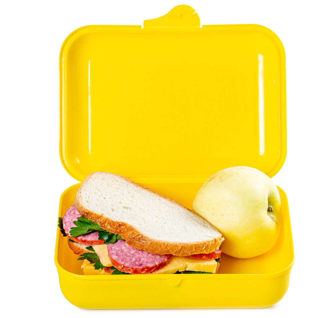 Бутерброд и яблоко в контейнере на белом фоне