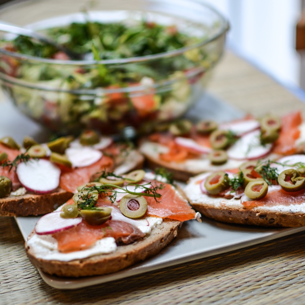 Бутерброды с маслом и красной рыбой на столе с салатом