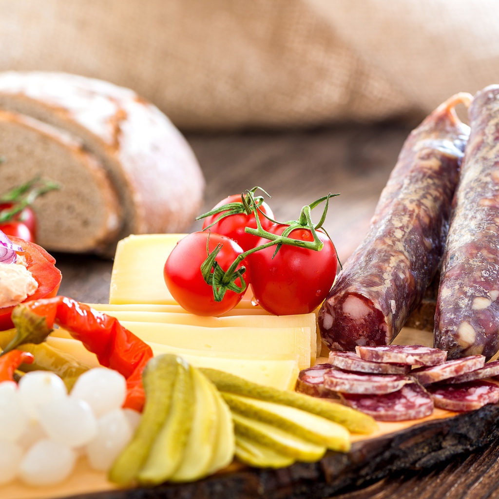 Колбаса на столе с огурцами, помидорами и перцем