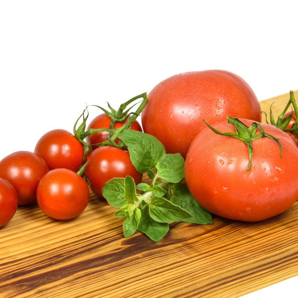 Маленькие и большие помидоры на деревянной доске 