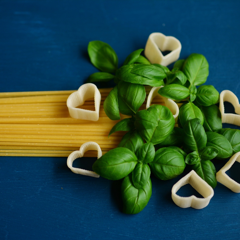 Spaghetti with basil on a blue background
