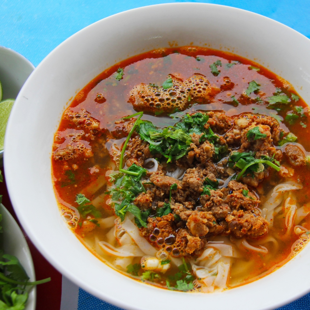 Острый суп с лапшой и мясом в тарелке с зеленью