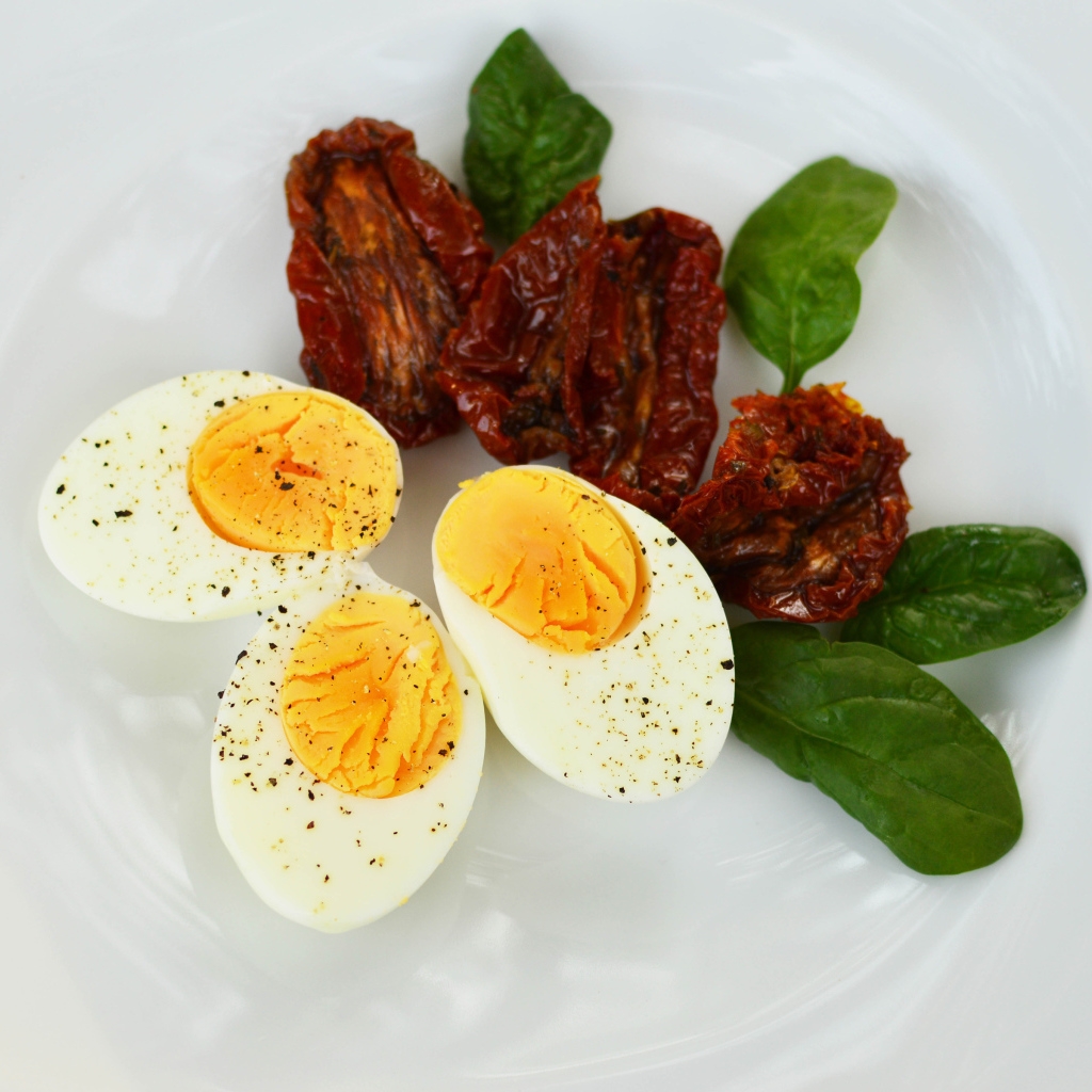 Вяленые помидоры на тарелке с базиликом и вареными яйцами