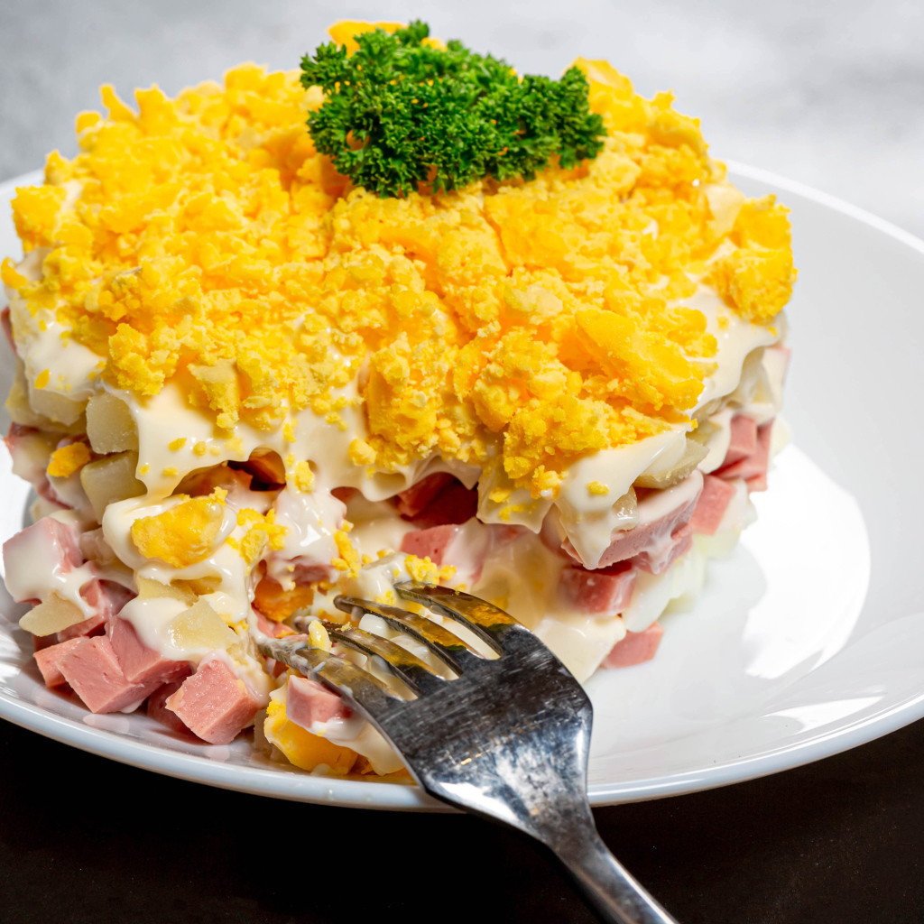 Вкусный салат на белой тарелке с вилкой