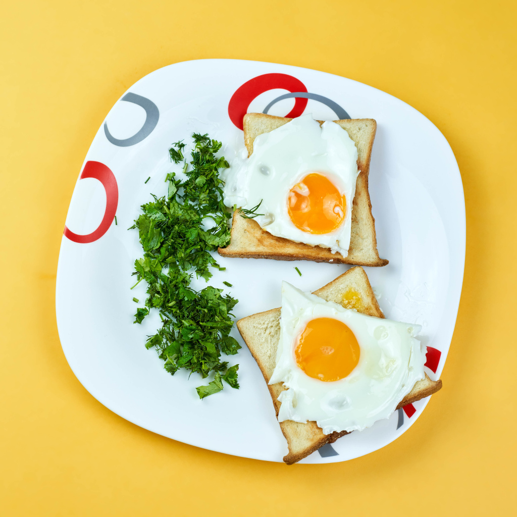 Тосты с яичницей на тарелке с зеленью петрушки 