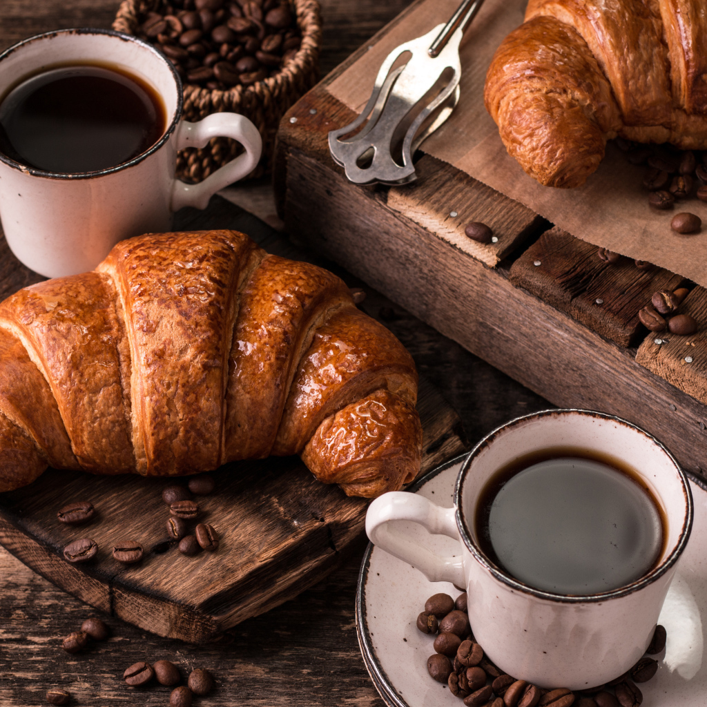 Две чашки кофе на столе с рогаликами и зернами 