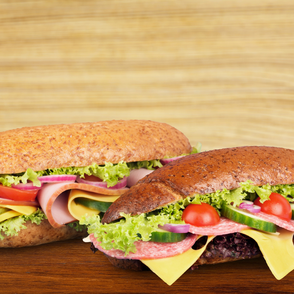 Два аппетитных сэндвича с колбасой и овощами на столе