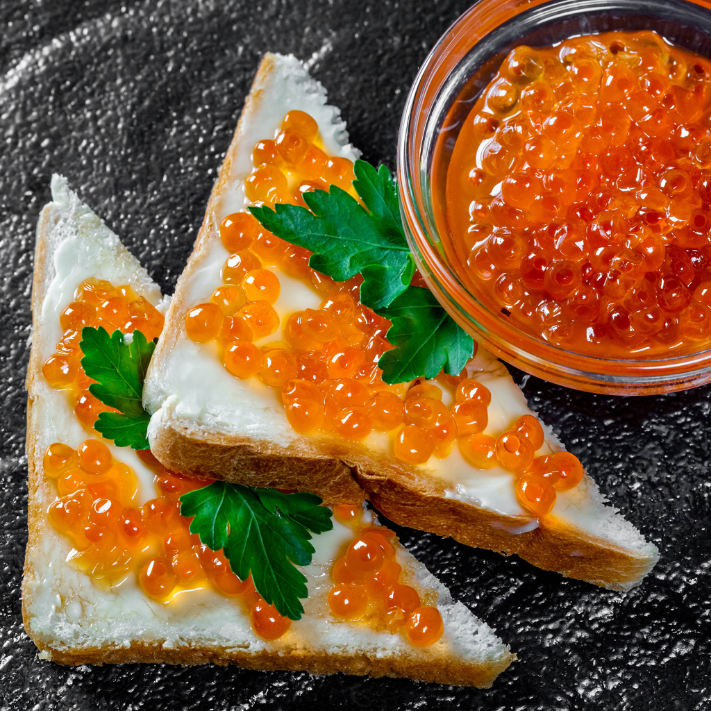 Два бутерброда с красной икрой на столе