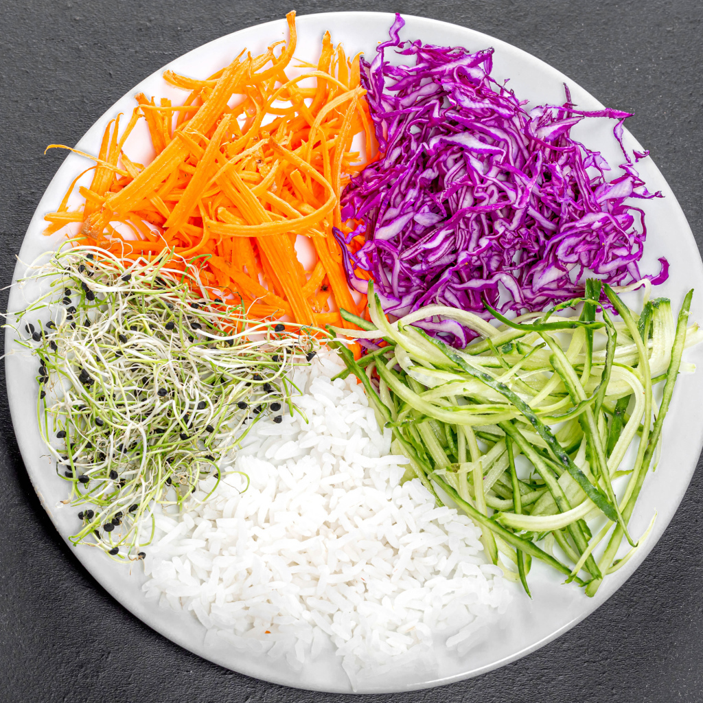 Овощи с рисом на большой  белой тарелке на сером столе 