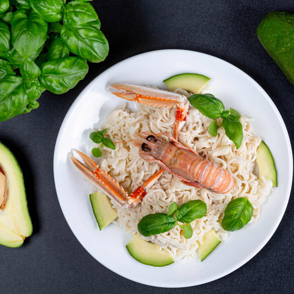 Vermicelli with lobster on a plate with avocado and basil leaves
