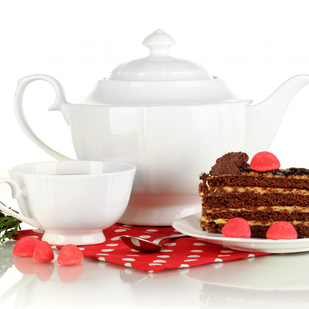 Белая чашка чая и чайник на столе с куском торта