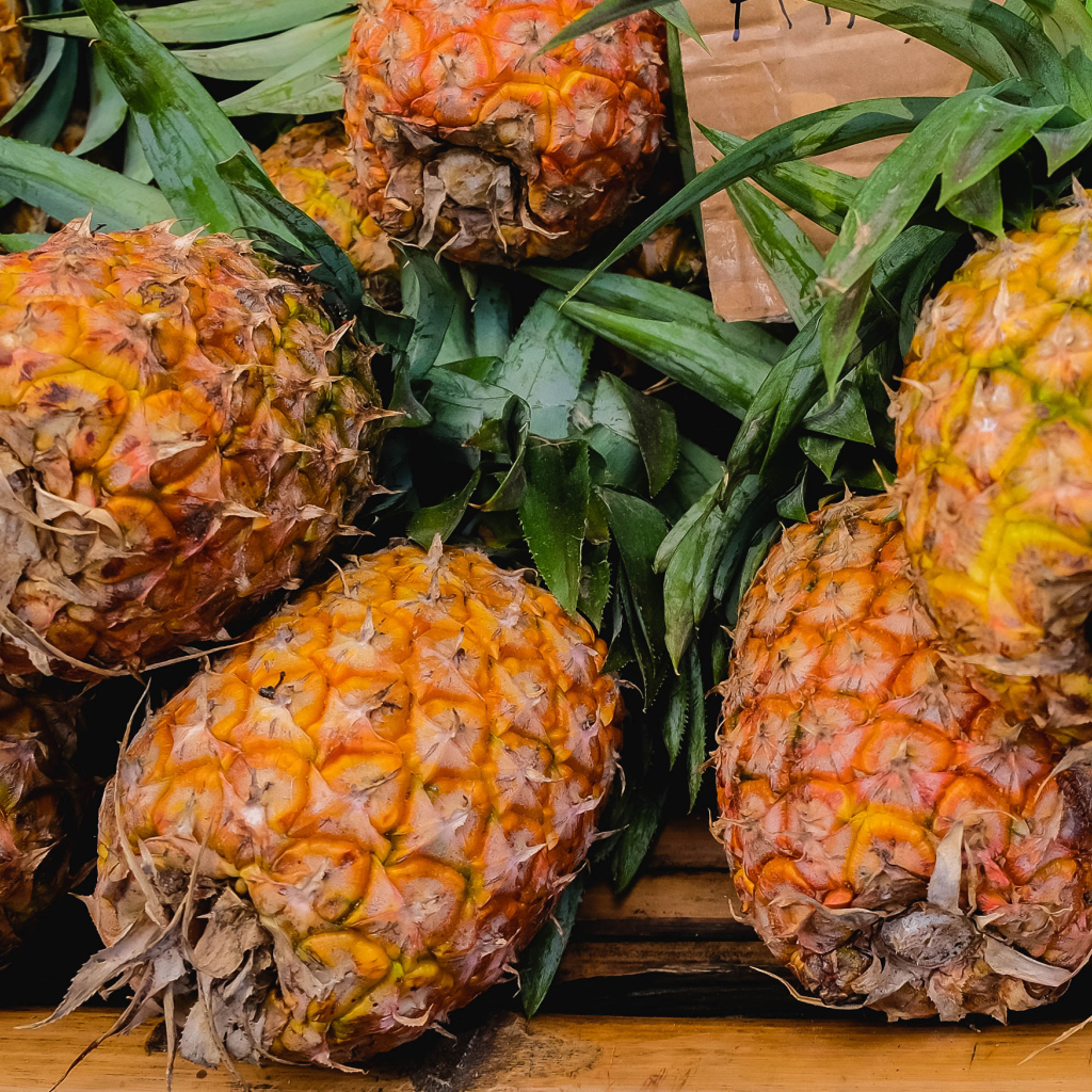 Много больших спелых ананасов на столе 