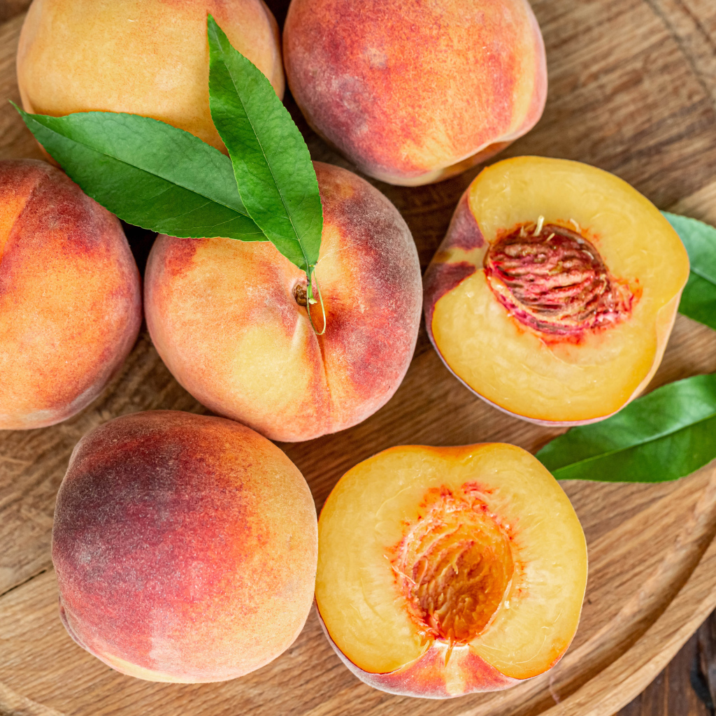 Аппетитные свежие персики на деревянной доске