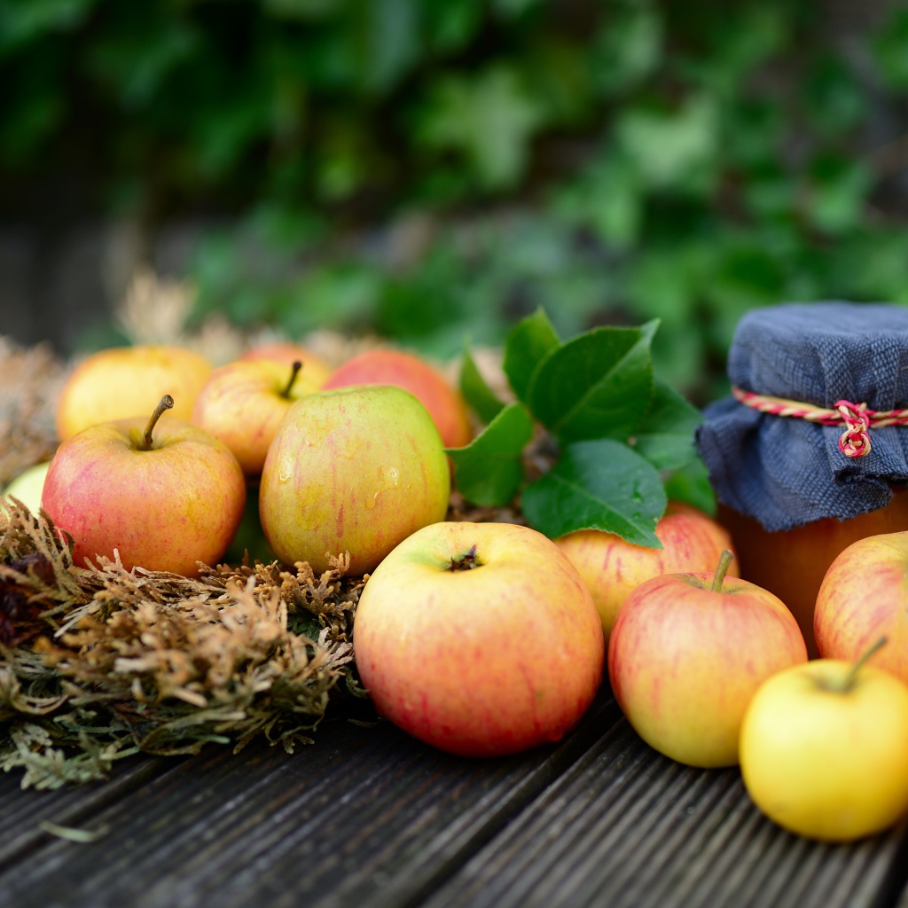 Яблоки и банка варенья на столе 