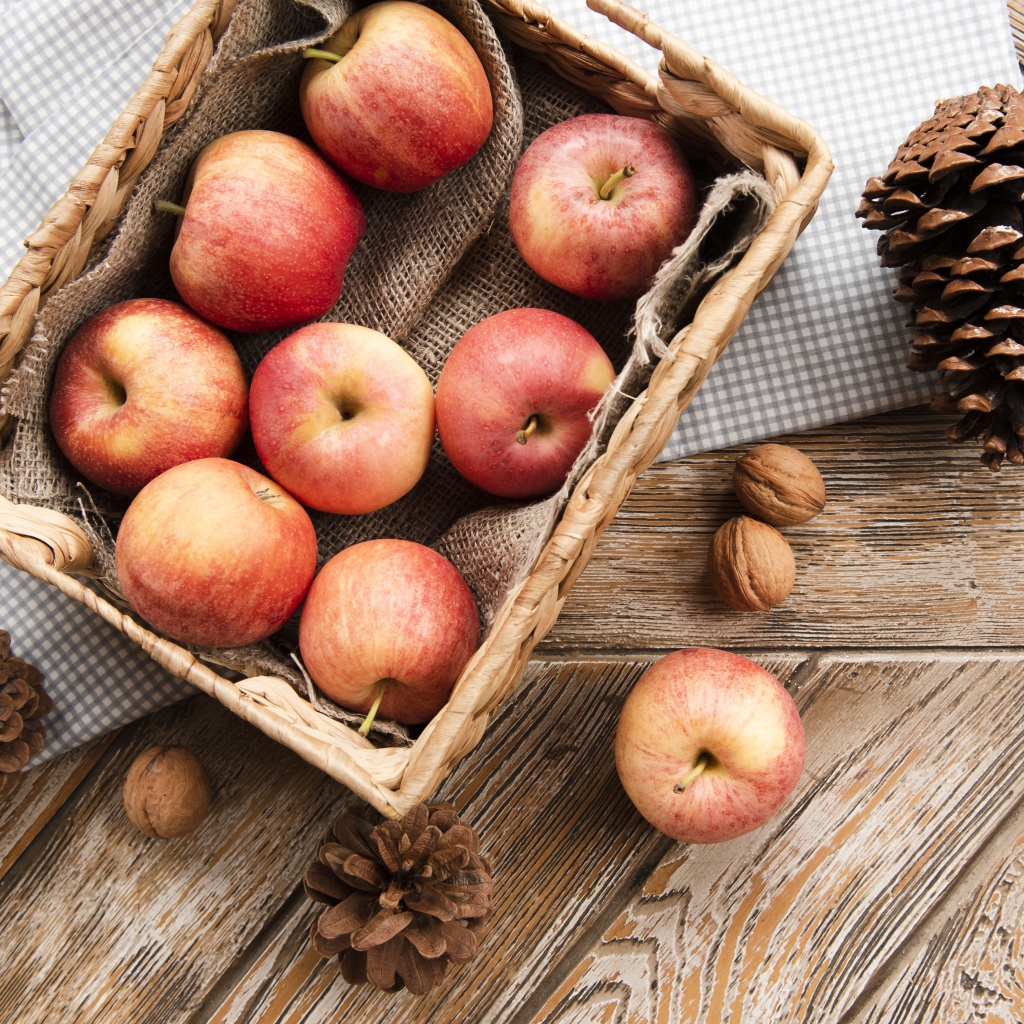 Корзина с яблоками на столе с сосновыми шишками