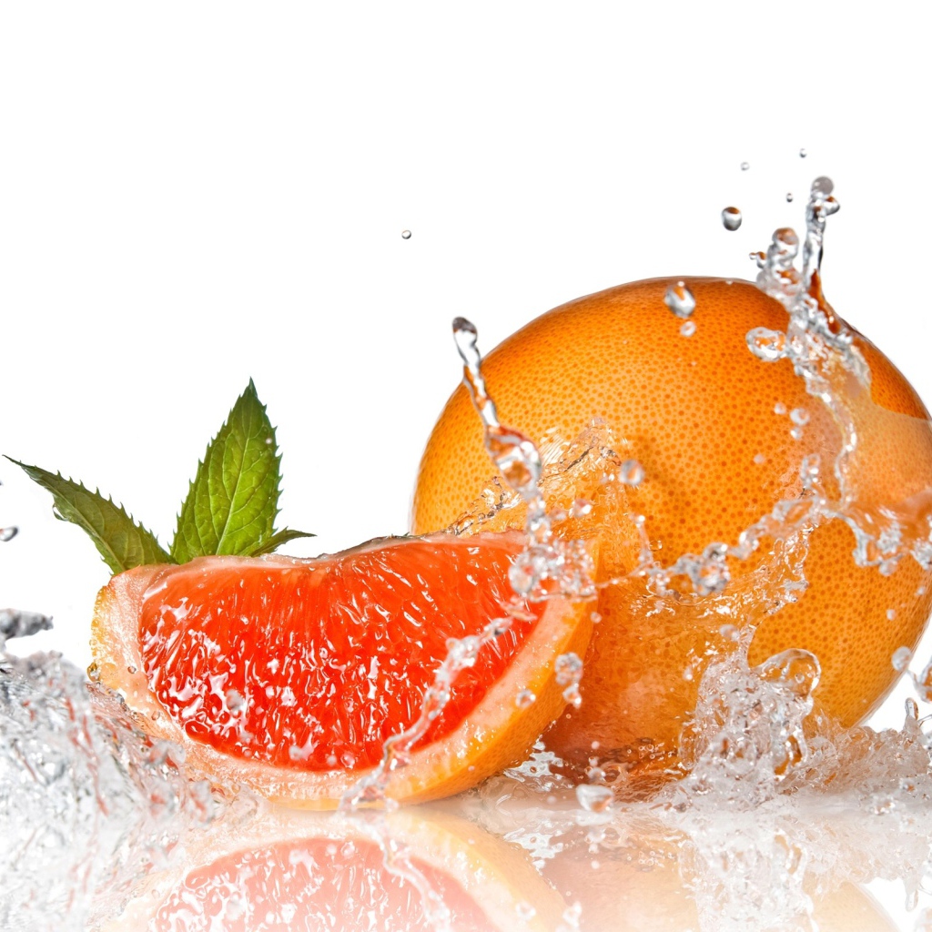 Большой спелый апельсин в брызгах воды на белом фоне