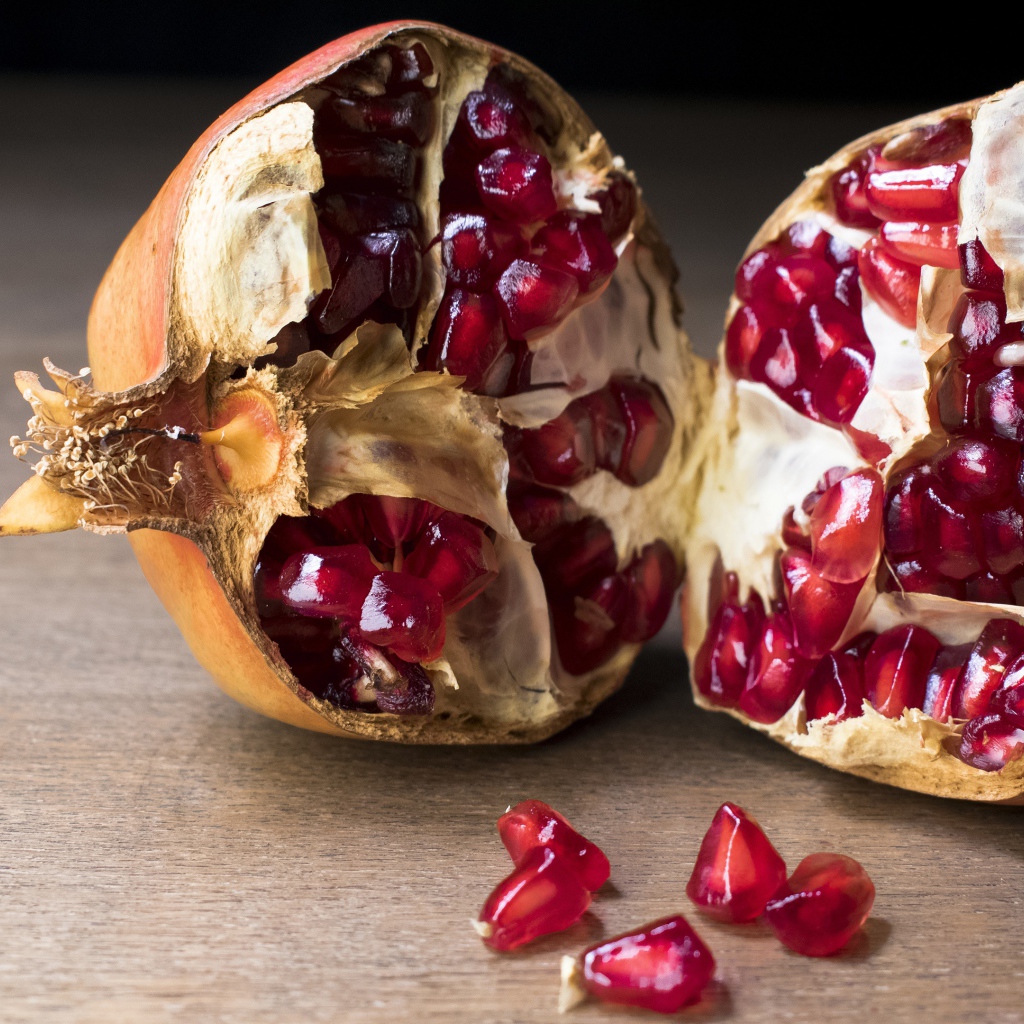 Разломанный красный гранат на столе 