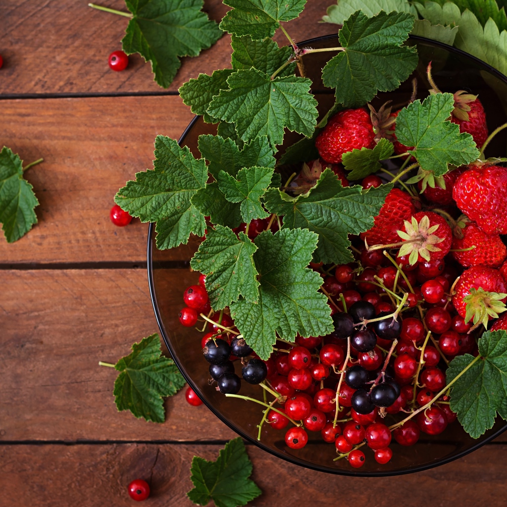 Ягоды смотродины в миске с клубникой и зелеными листьями