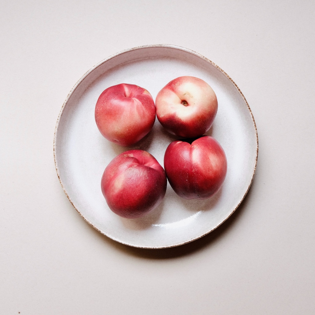 Four red ripe nectarines on a plate