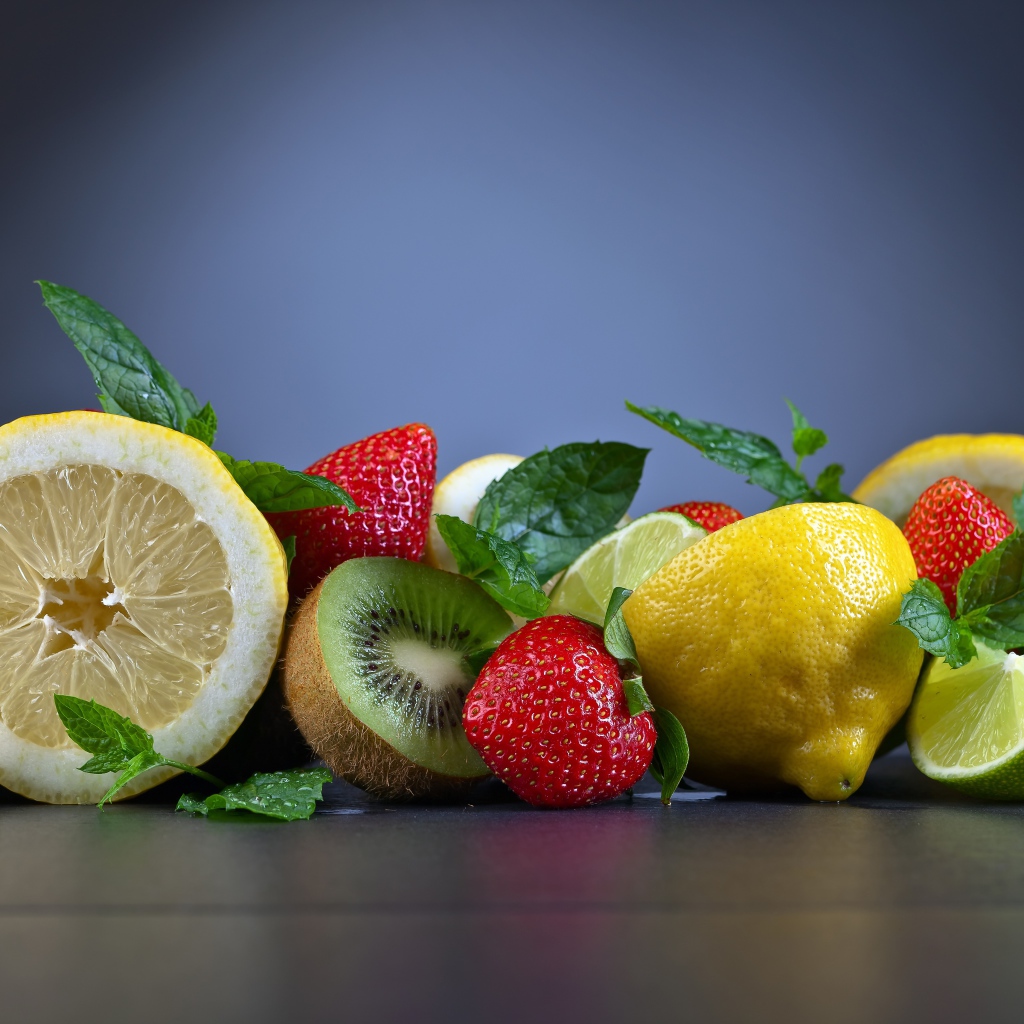 Лимоны на столе с киви и ягодами клубники 