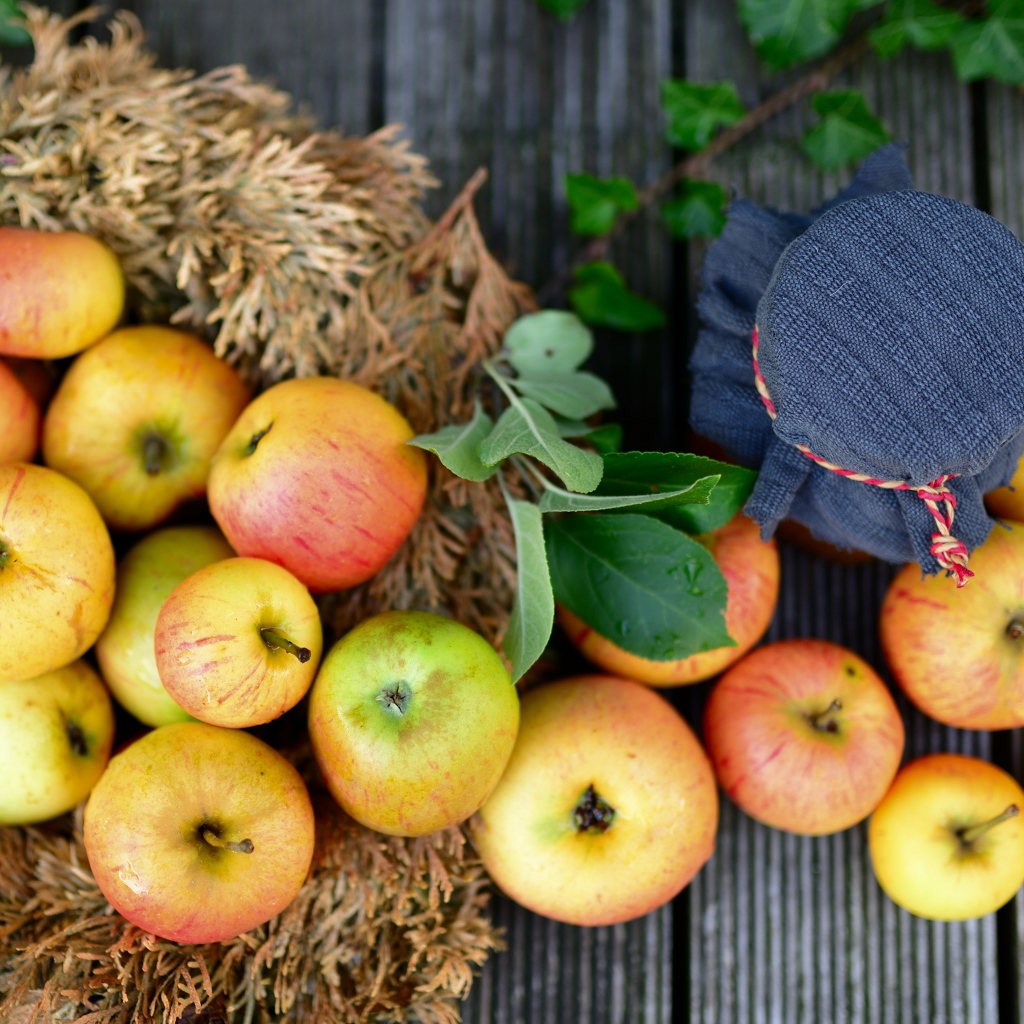 Много спелых яблок на столе с вареньем 