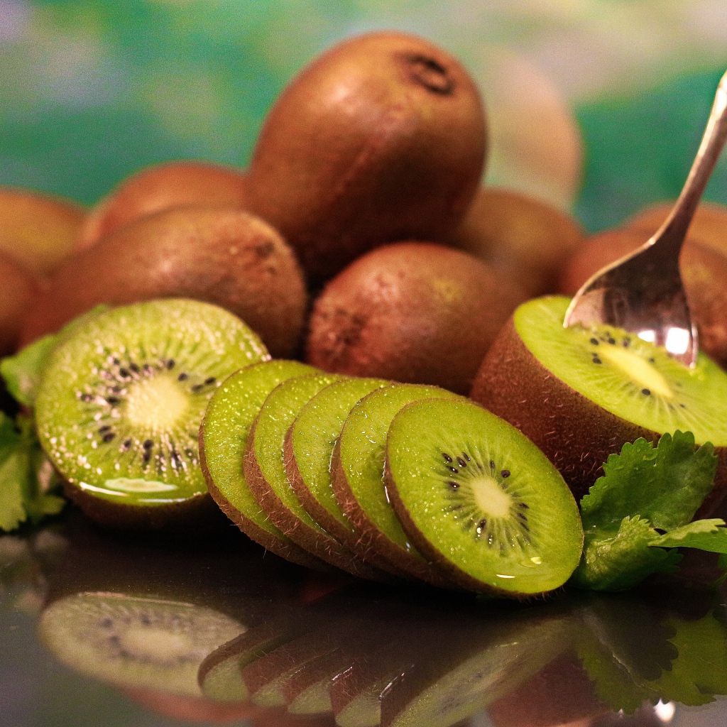 Много спелых плодов киви на столе с ложкой 