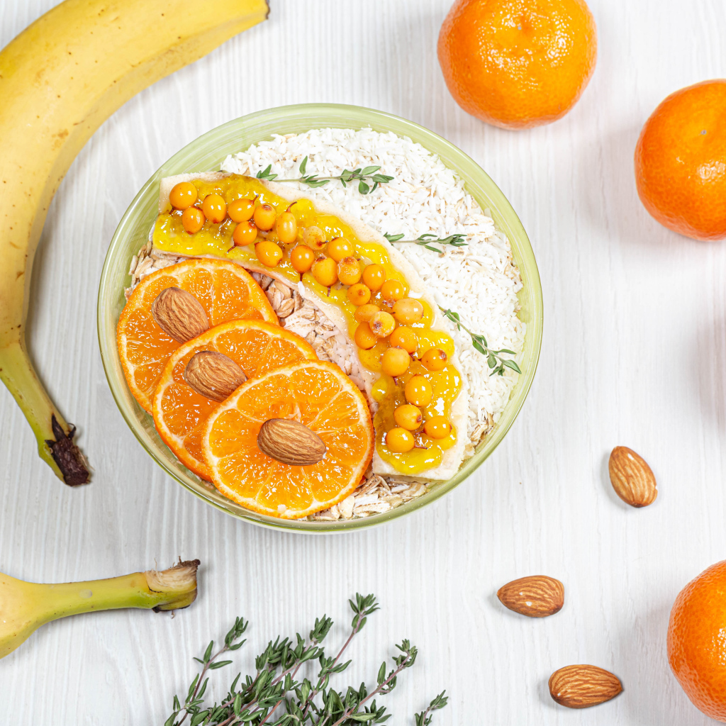 Мюсли с облепихой, бананом и апельсином на столе с фруктами