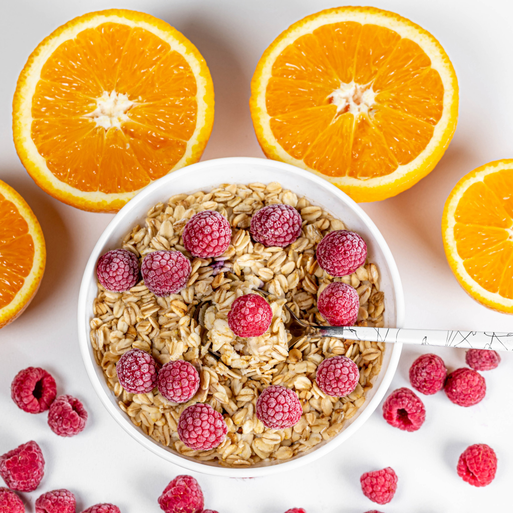 Овсяные хлопья с малиной на белом фоне с апельсинами