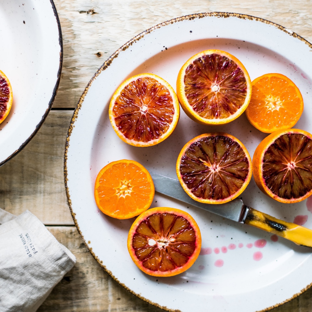 Половинки апельсина на тарелке с ножом