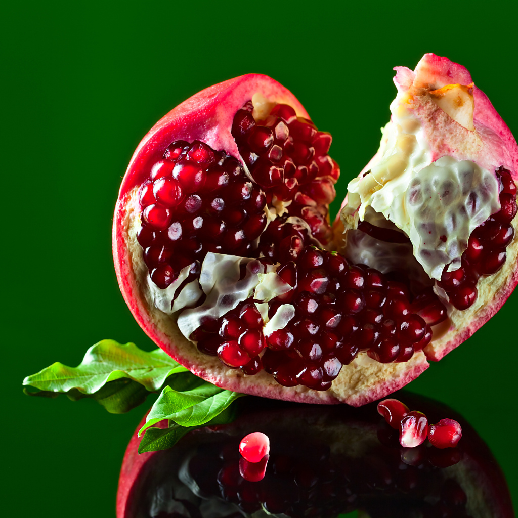Очищенный гранат на зеленом фоне